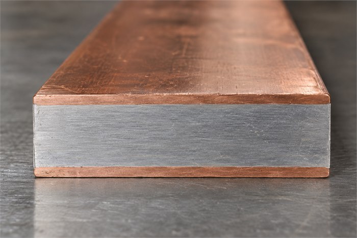 Close-up of a copper clad aluminum flat bar showing copper faces and an aluminum core.